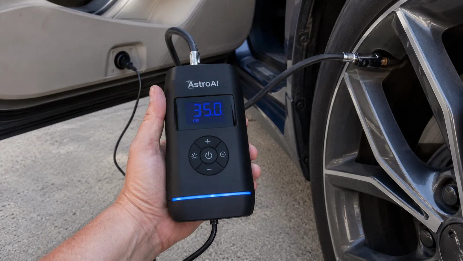 Hand holding the AstroAI inflator's digital display close up while the hose is threaded onto a tire valve stem