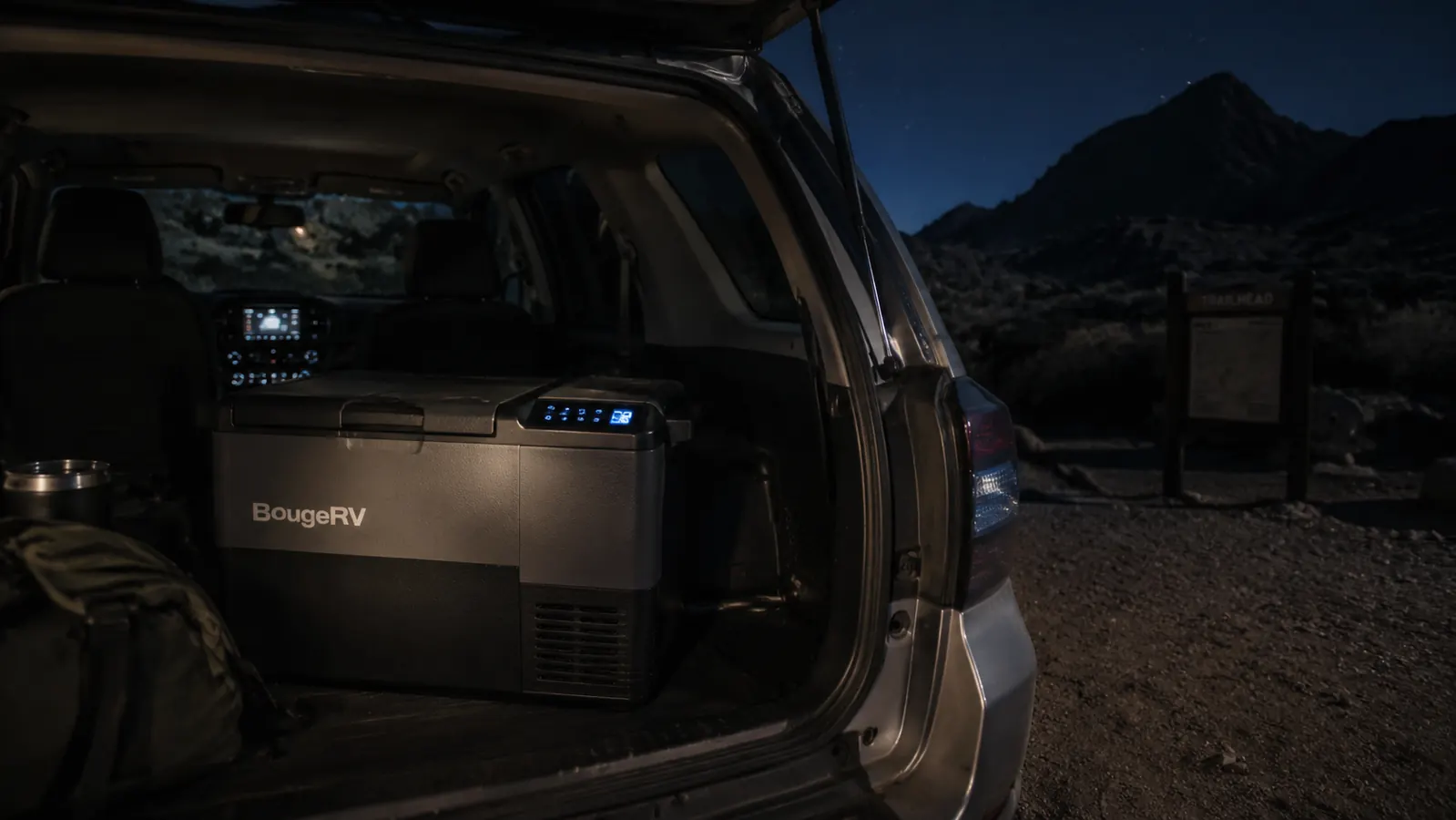 BougeRV 12V fridge glowing faintly in the dark cargo area of an SUV parked at a trailhead overnight