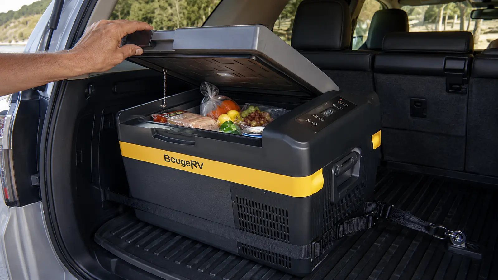 Hand lifting the lid of the BougeRV fridge strapped into the cargo area of a 4Runner