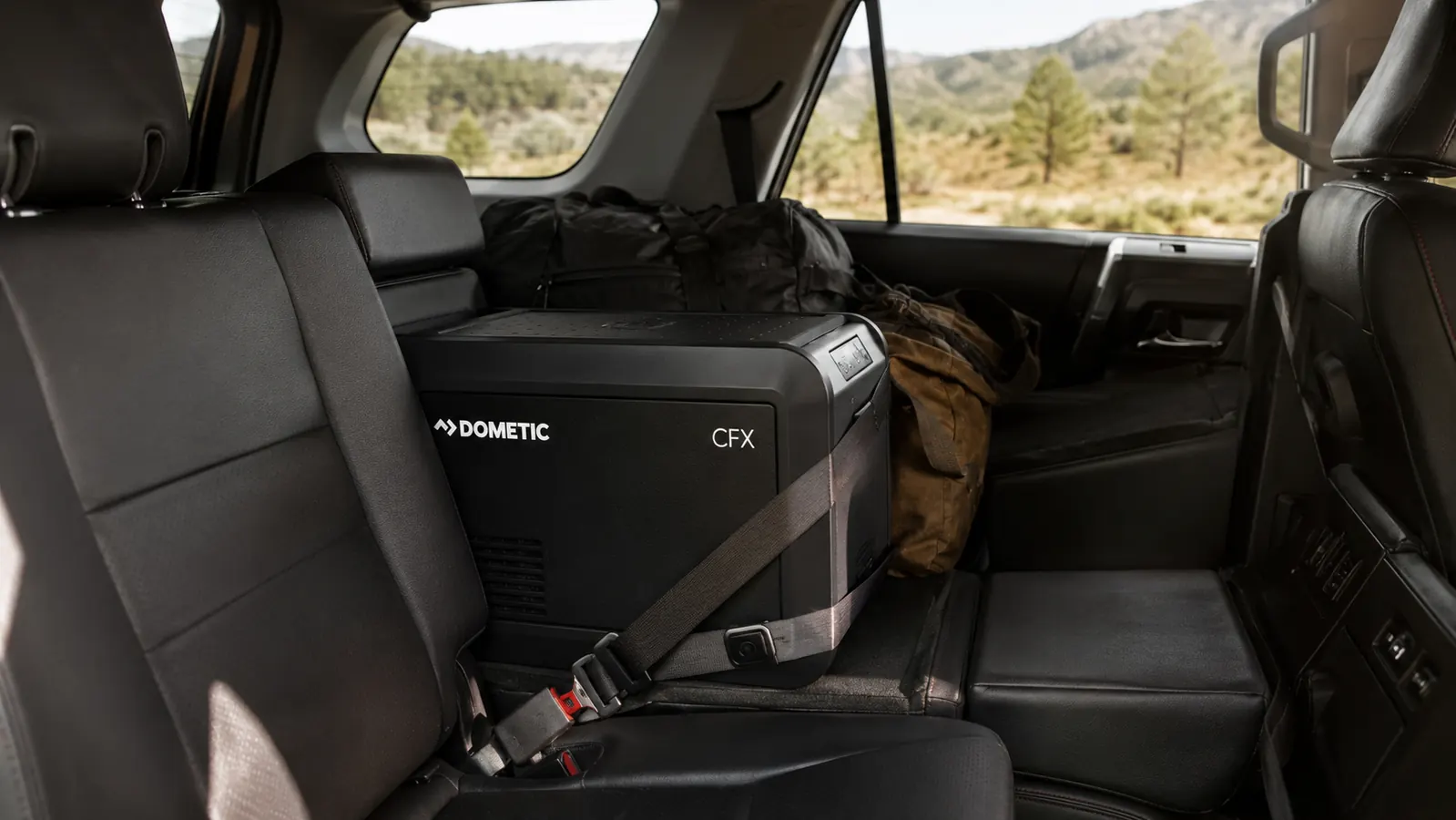 The BougeRV fridge loaded into the back seat footwell of a 4Runner with a seatbelt strap securing it, packed for a multi-day drive