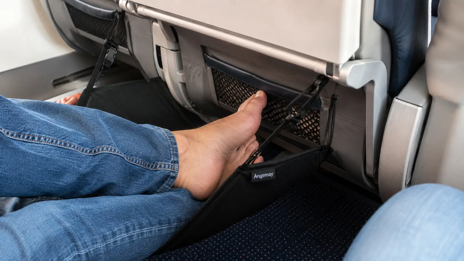 Memory foam foot hammock strapped to an airplane tray table with feet resting inside it